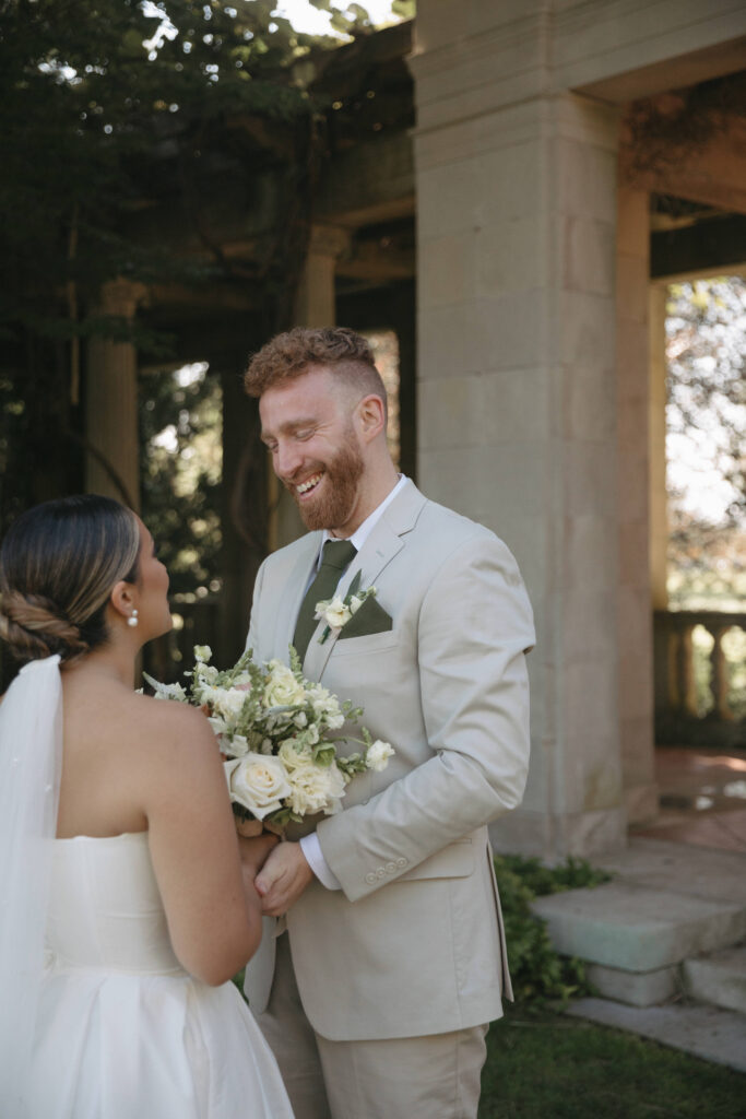 Documentary and editorial wedding photography from garden summer outdoor wedding at Eolia Mansion in Connecticut. Photos taken by Suz Lundeen Photo - destination wedding, family, and maternity photographer based in New England and the Midwest. Photo of groom in khaki suit admiring his bride at their first look.