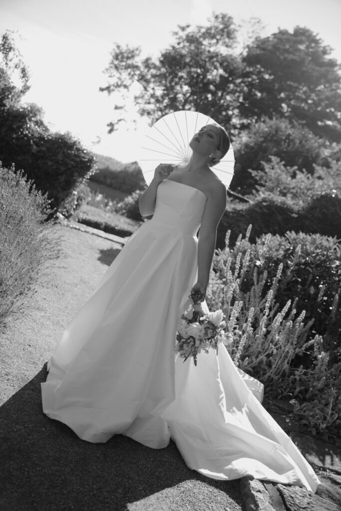 Documentary and editorial wedding photography from garden summer outdoor wedding at Eolia Mansion in Connecticut. Photos taken by Suz Lundeen Photo - destination wedding, family, and maternity photographer based in New England and the Midwest. Editorial bridal portrait of bride with her parasol in direct sunlight.