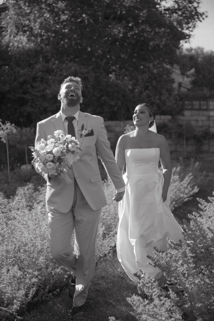 Documentary and editorial wedding photography from garden summer outdoor wedding at Eolia Mansion in Connecticut. Photos taken by Suz Lundeen Photo - destination wedding, family, and maternity photographer based in New England and the Midwest. Posed couples photo of bride and groom in a lavender garden exiting their wedding ceremony.