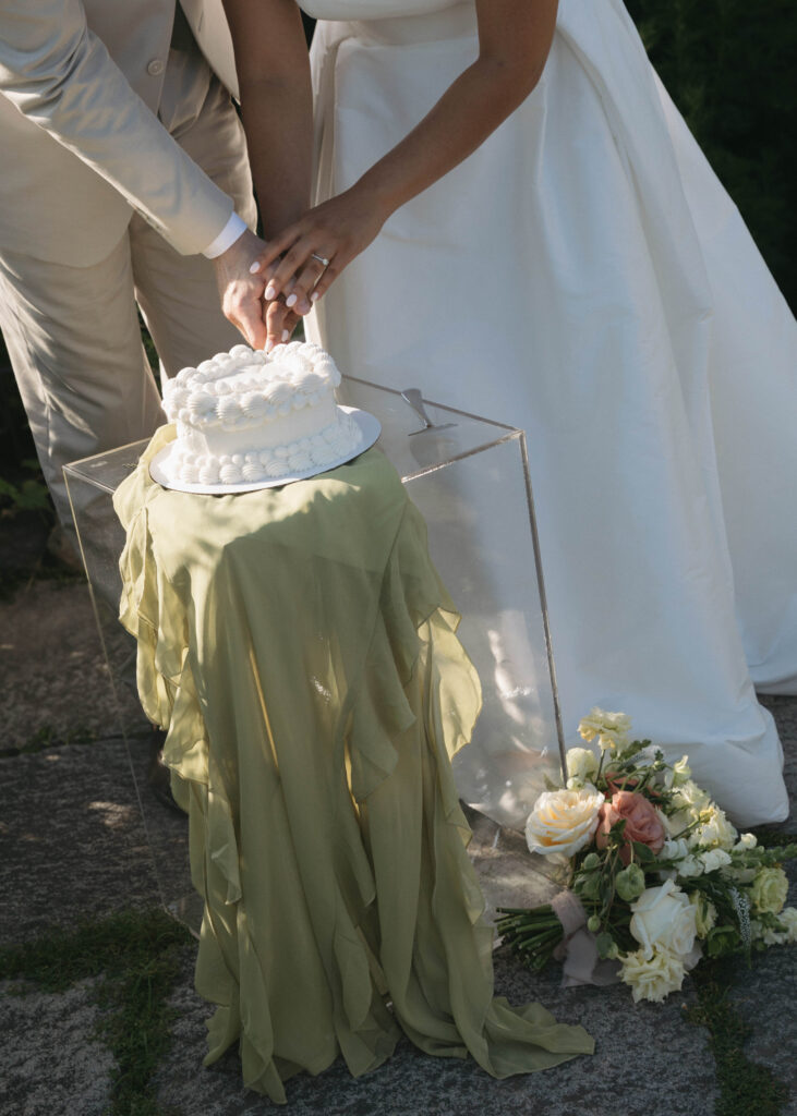 Documentary and editorial wedding photography from garden summer outdoor wedding at Eolia Mansion in Connecticut. Photos taken by Suz Lundeen Photo - destination wedding, family, and maternity photographer based in New England and the Midwest. Candid photo of couple cutting their wedding cake at their outdoor garden reception.